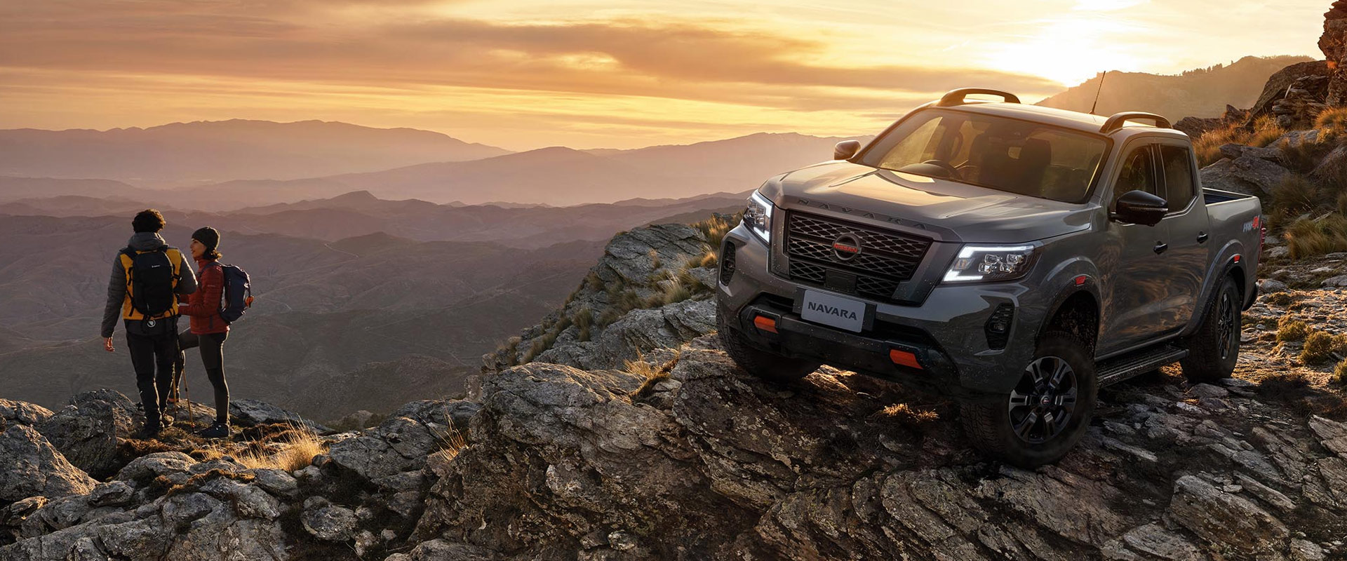 A Nissan Navara ute parked on rocks by sunset