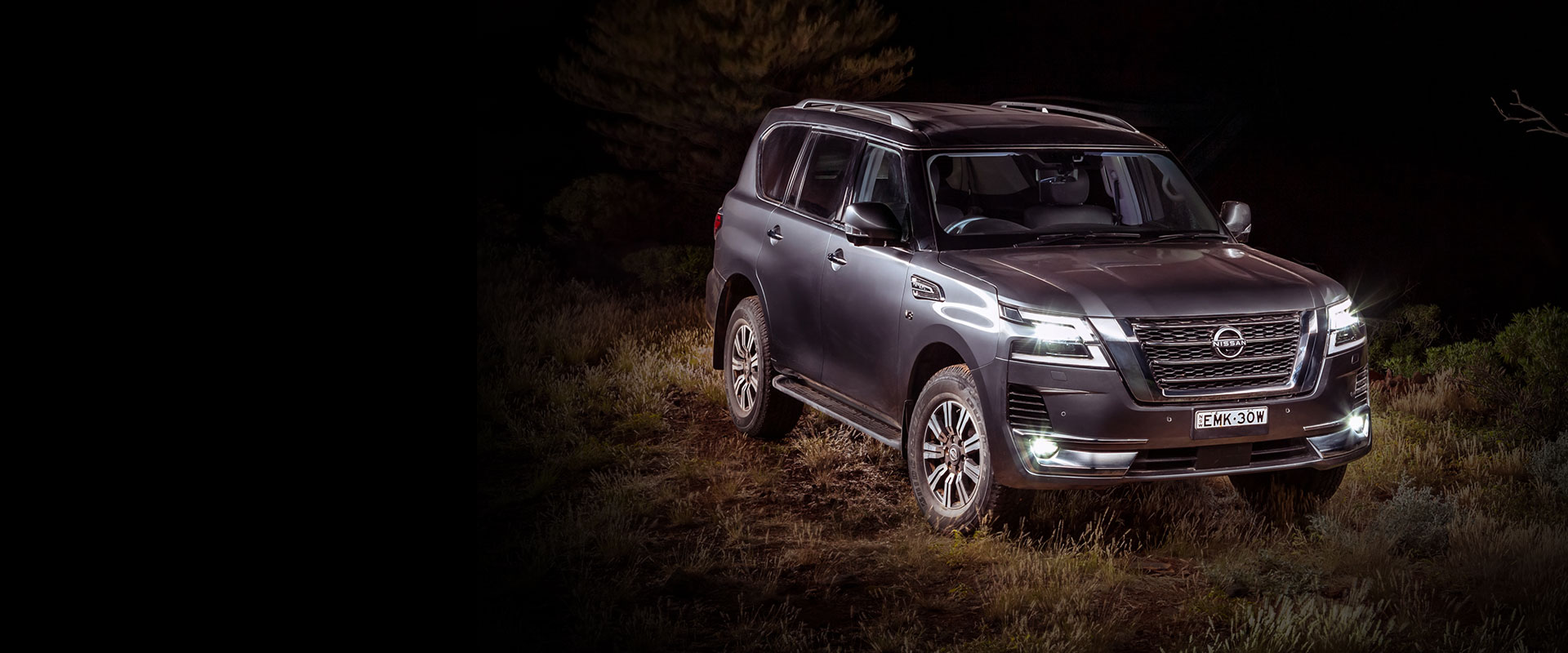 A silver SUV parked at night illuminated by a spot light