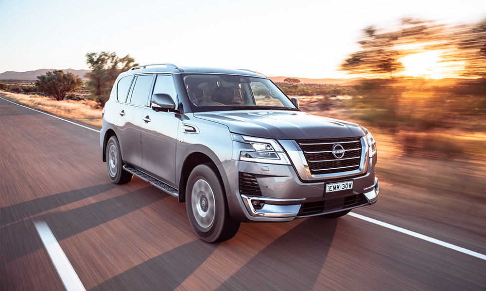 A Silver Patrol SUV driving on a desert road