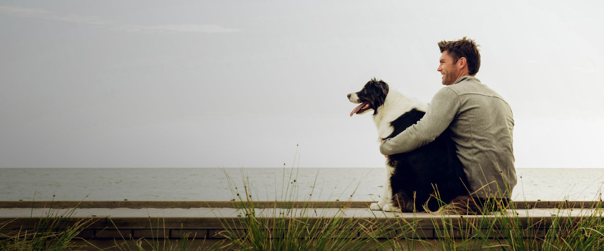 A man and his dog sitting by ocean